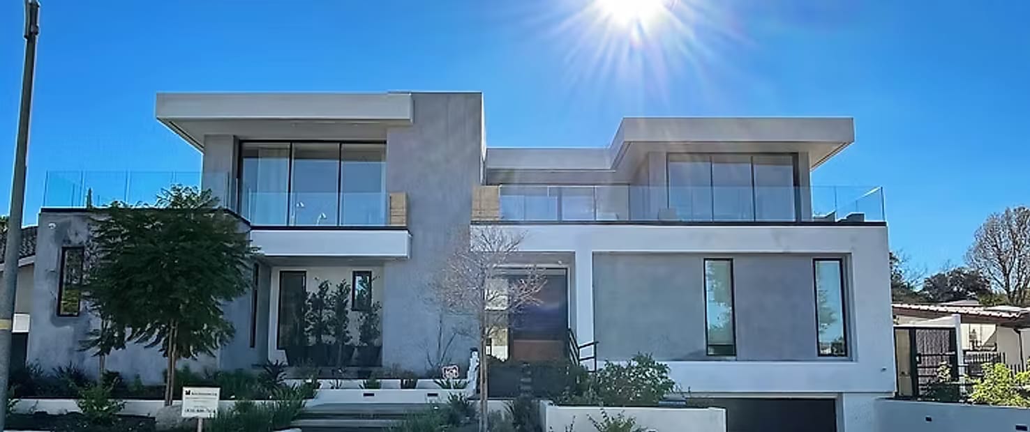 A two-story modern custom home built by Reuss Enterprises, photographed from the street in bright daylight